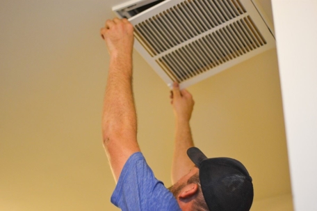HVAC technician changing one of a house's air filters.