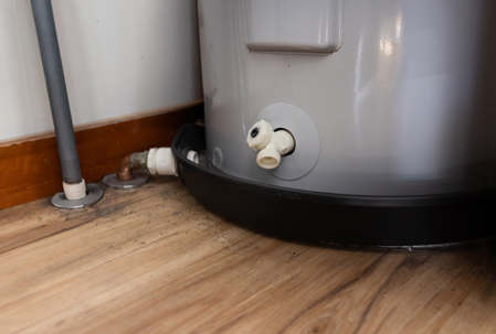 A electric water heater drain valve above the drain pan.