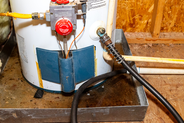 A close-up of a hose attached to the drain of a water heater during the flushing process. | Blazer Heating, Air, and Plumbing
